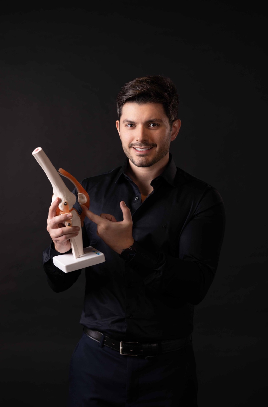 Dr. Tasso Alacón apontando para o ligamento em um modelo anatômico de joelho